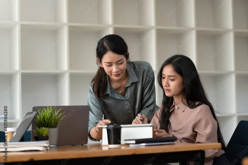 Two Asian businesswoman brainstorm work analyze consult collaborate at the office. Two Asian businesswoman brainstorm work analyze consult collaborate at the office.