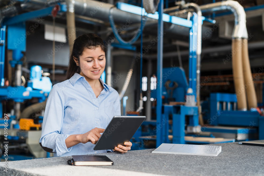 Smiling expertise using digital tablet while standing at industry Smiling expertise using digital tablet while standing at industry