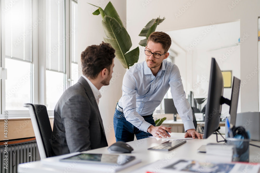 © Daniel Ingold/Westend61 - Businessman discussing over document with male colleague at office