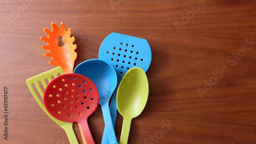 A variety of colorful kitchen utensils on a wooden surface.