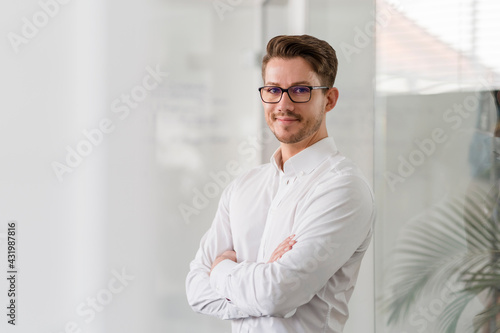 Confident male entrepreneur with arms in office