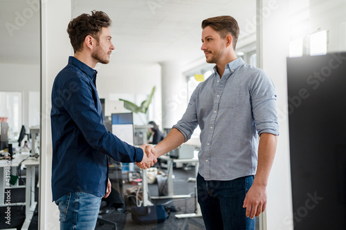 Handsome business people shaking hands in office photo