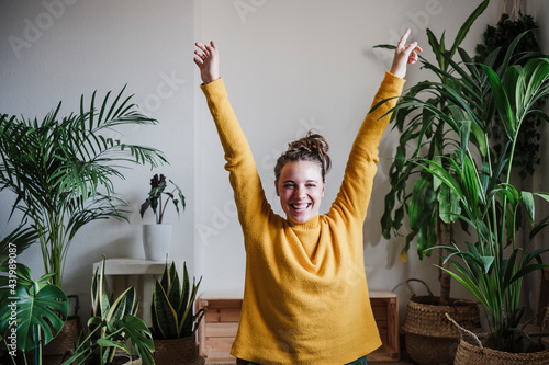Carefree woman with hand raised sitting at home photo