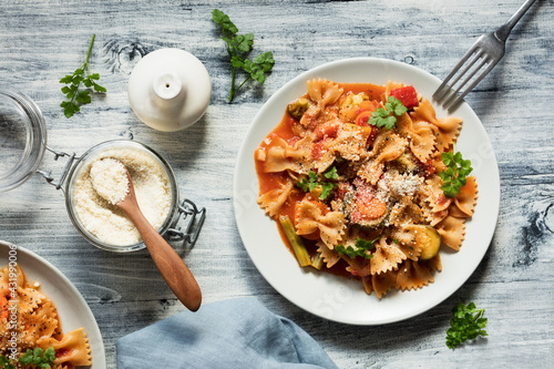 Two plates of bow tie pasta with vegetables and vegan Parmesan photo