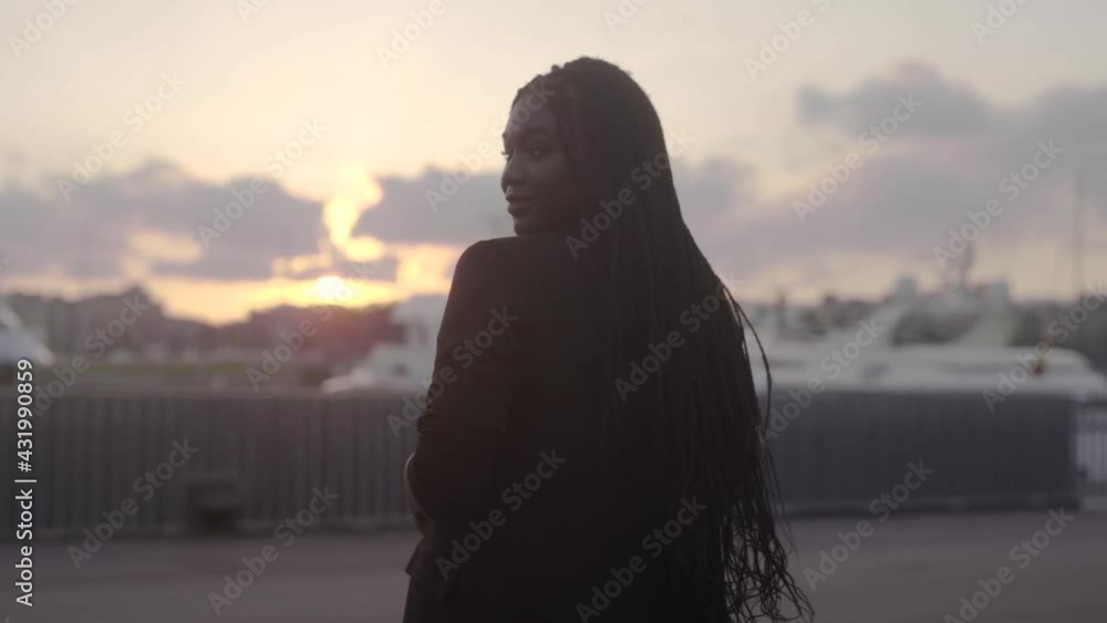 Attractive black woman walking on city promenade in twilight Attractive black woman walking on city promenade in twilight