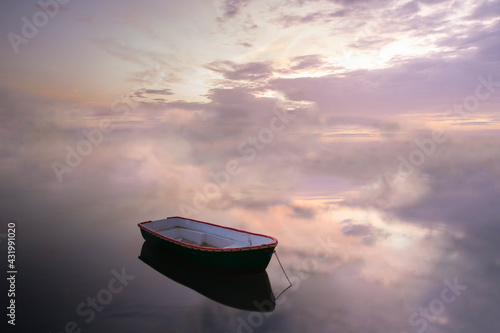 Boat moored on calm sea against cloudy sky during sunset photo