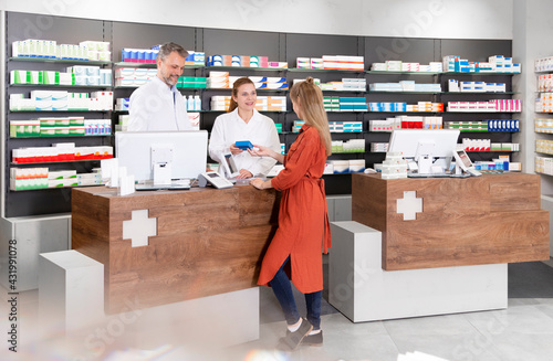 Female customer purchasing medicine from pharmacists in store photo