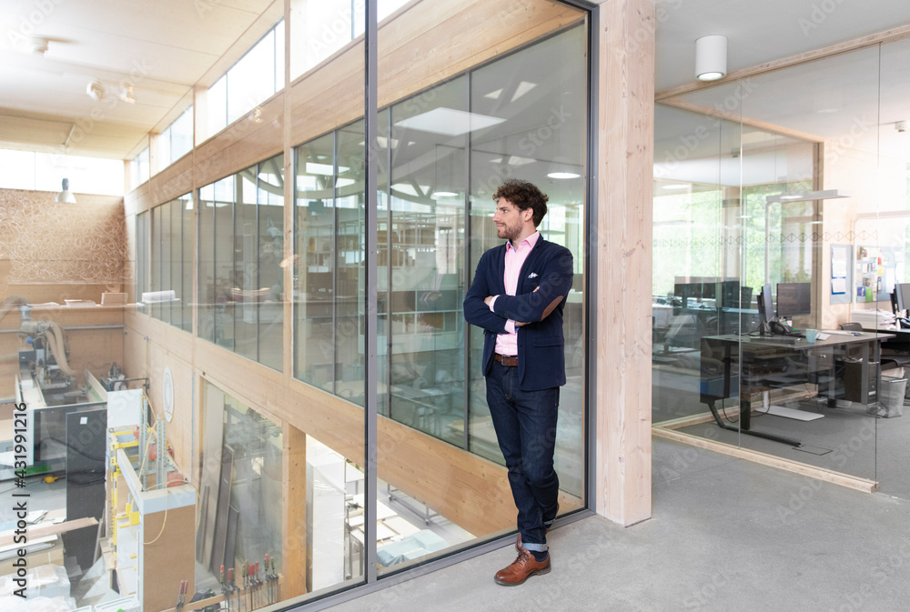 Male entrepreneur looking through glass wall in factory Male entrepreneur looking through glass wall in factory