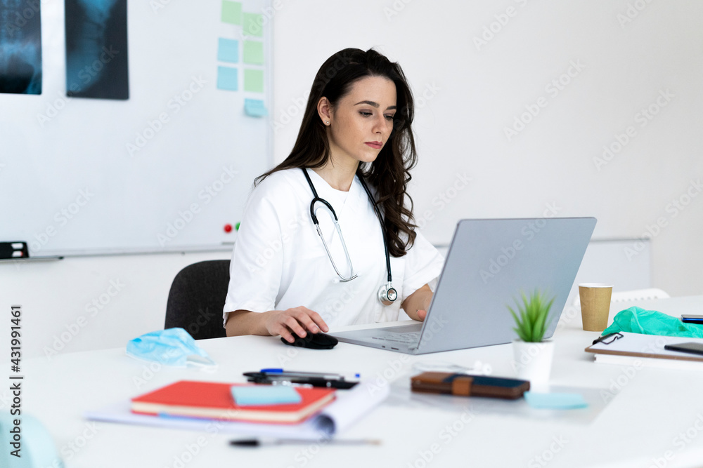 Female doctor consulting online through laptop in clinic Female doctor consulting online through laptop in clinic