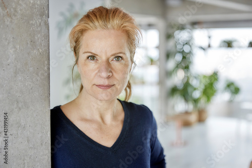 Woman with hazel eyes leaning on wall at home