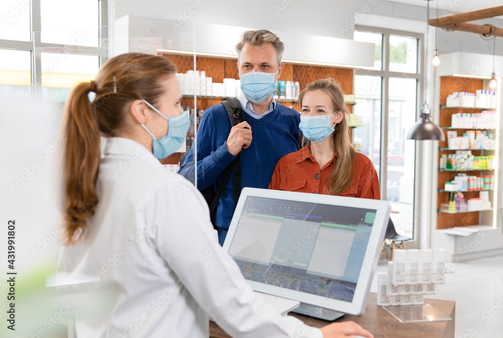 Female cashier with customers in protective face masks at pharmacy checkout Female cashier with customers in protective face masks at pharmacy checkout