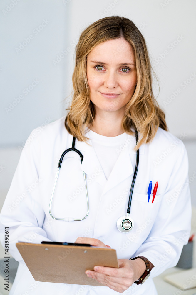 Blond female doctor with clipboard at medical clinic Blond female doctor with clipboard at medical clinic