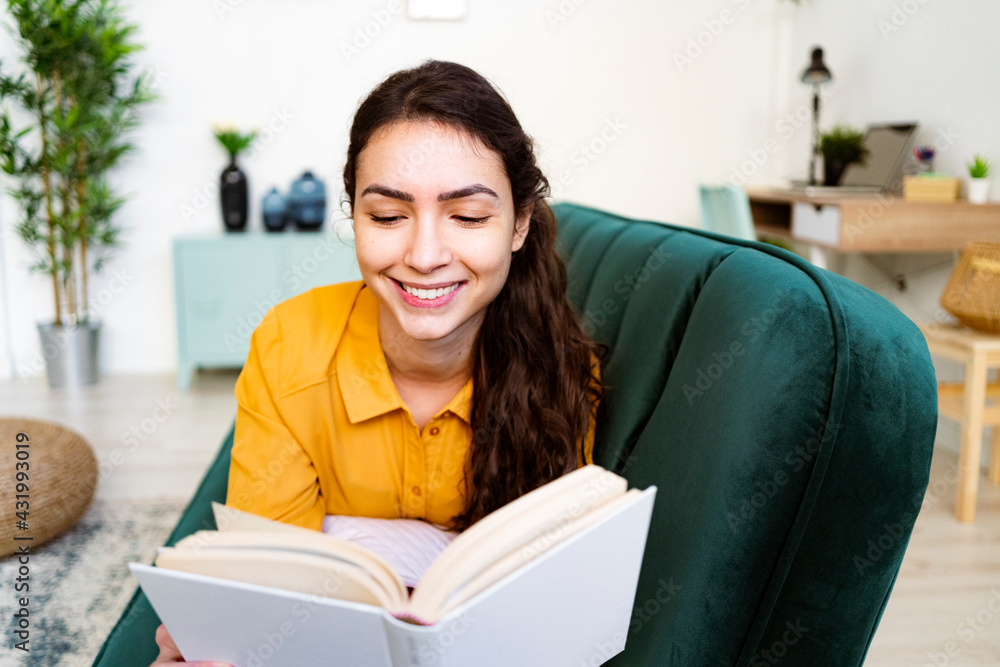 Young woman reading book while lying on sofa at home Young woman reading book while lying on sofa at home