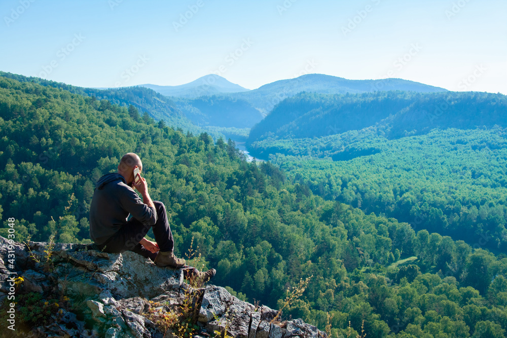Man talking on a mobile phone on a mountain landscape background