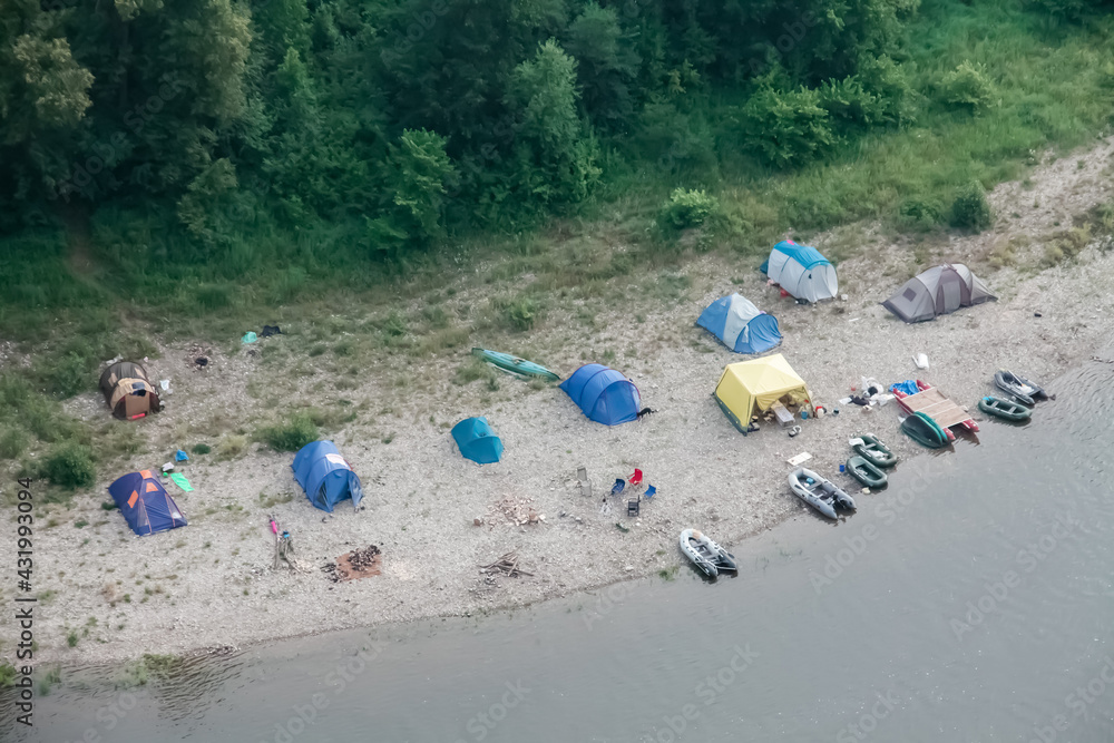 Camping tents on the beach. Tourists rafting on the river on a halt