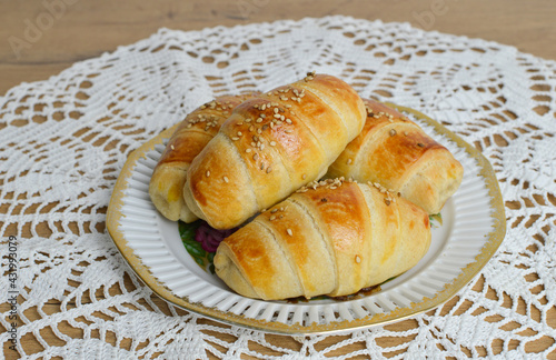 Traditional Serbian  homemade rolls with sesame (kiflice) on the vintage plate, on the rustic crochet tablecloth, close up photo