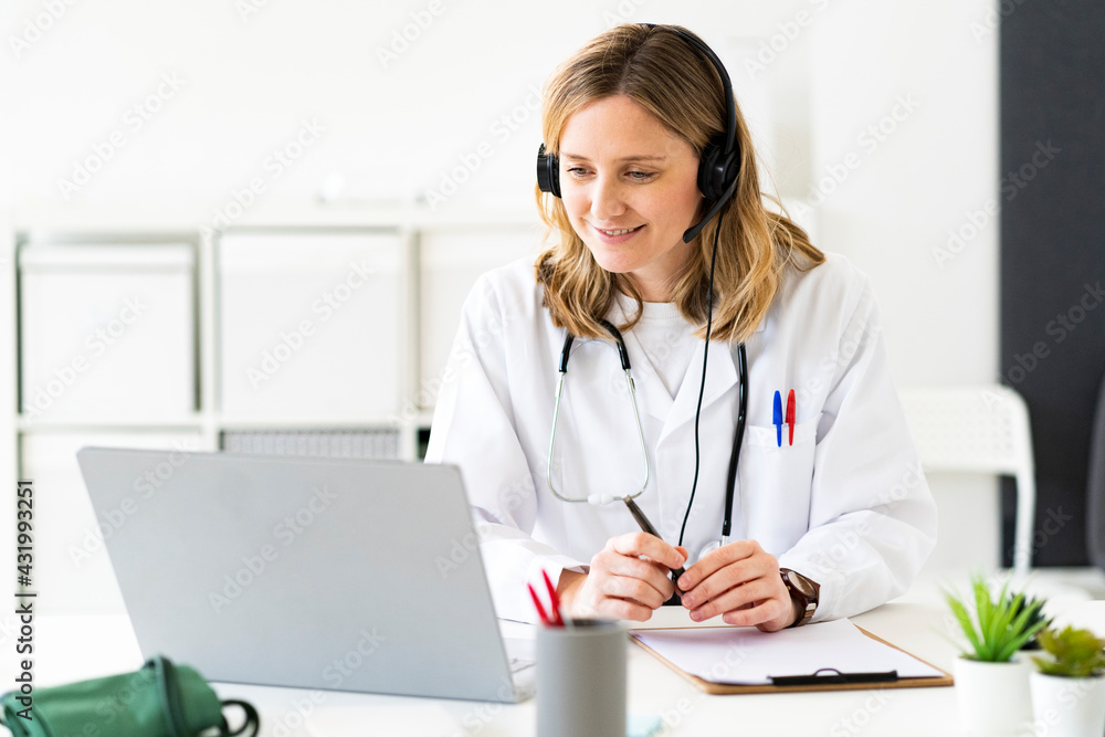 Blond female doctor giving online consultation on laptop in medical clinic Blond female doctor giving online consultation on laptop in medical clinic
