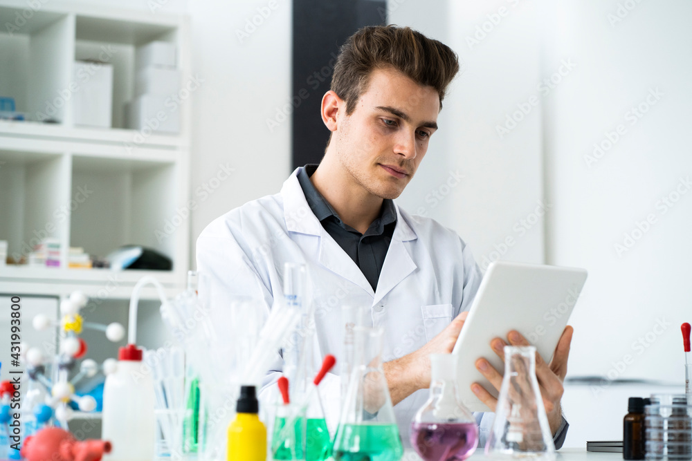 Male scientist using digital tablet while working in laboratory Male scientist using digital tablet while working in laboratory