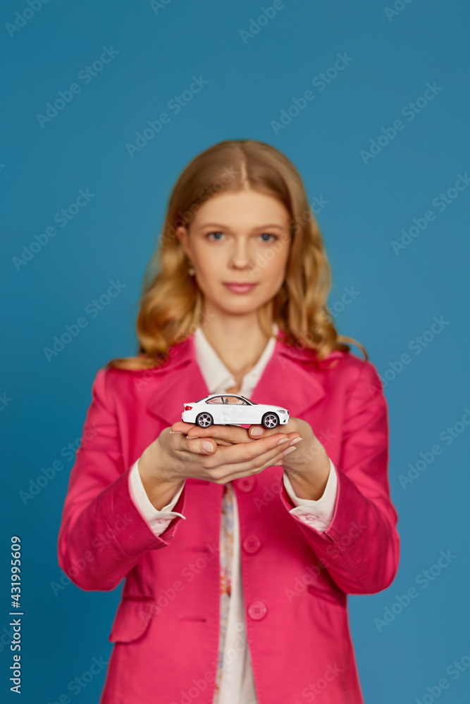 beautiful blonde woman in pink jacket holding a little car beautiful blonde woman in pink jacket holding a little car