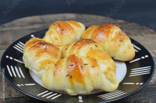 Homemade  Serbian dinner rolls( kiflice) withe caraway seeds on the black and white plate photo