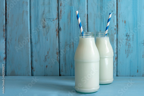 Milk bottle for Jewish holiday Shavuot on blue wooden background with copy space.