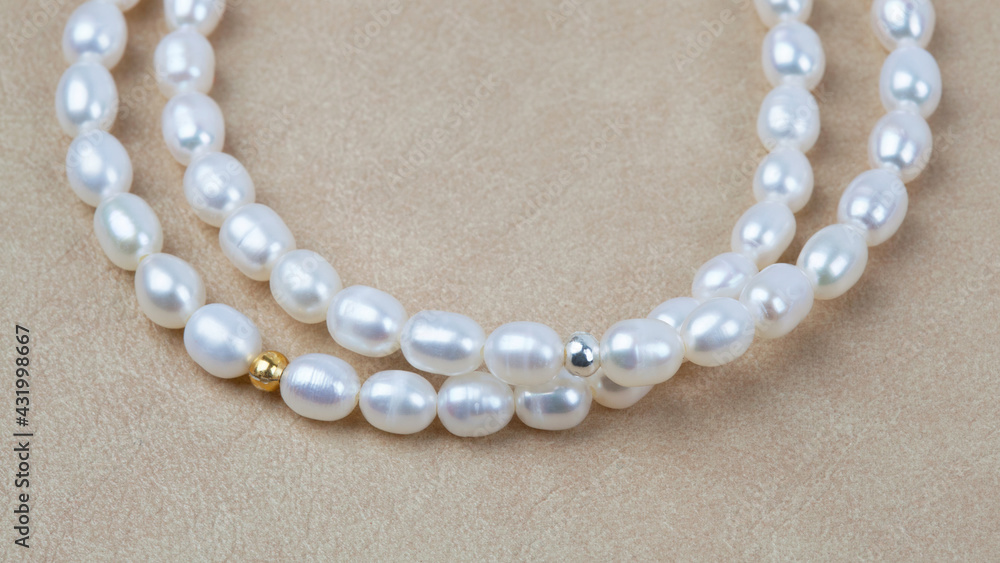 Luxury elegant baroque pearl bracelets on beige textured leather background Luxury elegant baroque pearl bracelets on beige textured leather background