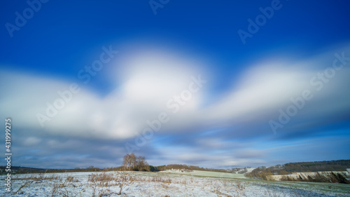 Long exposure winter snow field panorama with beautiful day sky