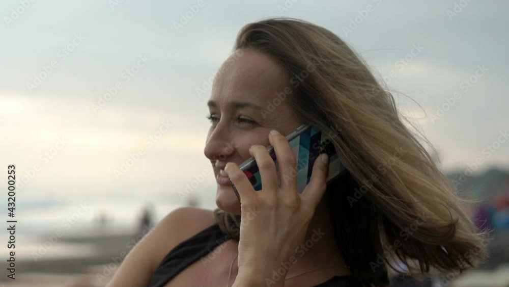 Beautiful young woman talking on cellphone at beach cafe Beautiful young woman talking on cellphone at beach cafe