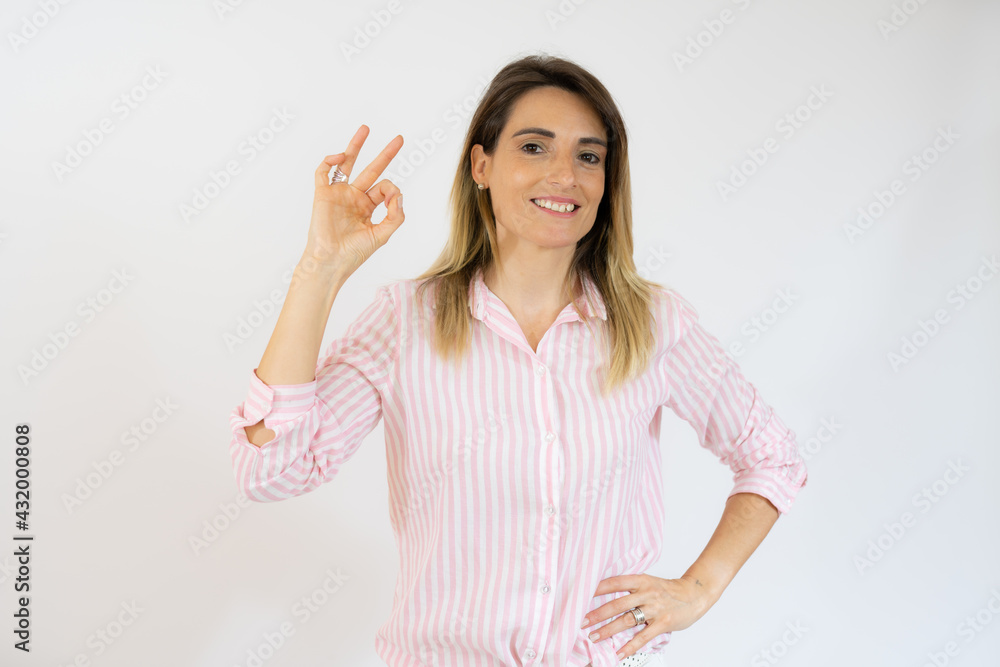 Smiling woman in casual shirt with okay sign isolated over white background. Smiling woman in casual shirt with okay sign isolated over white background.