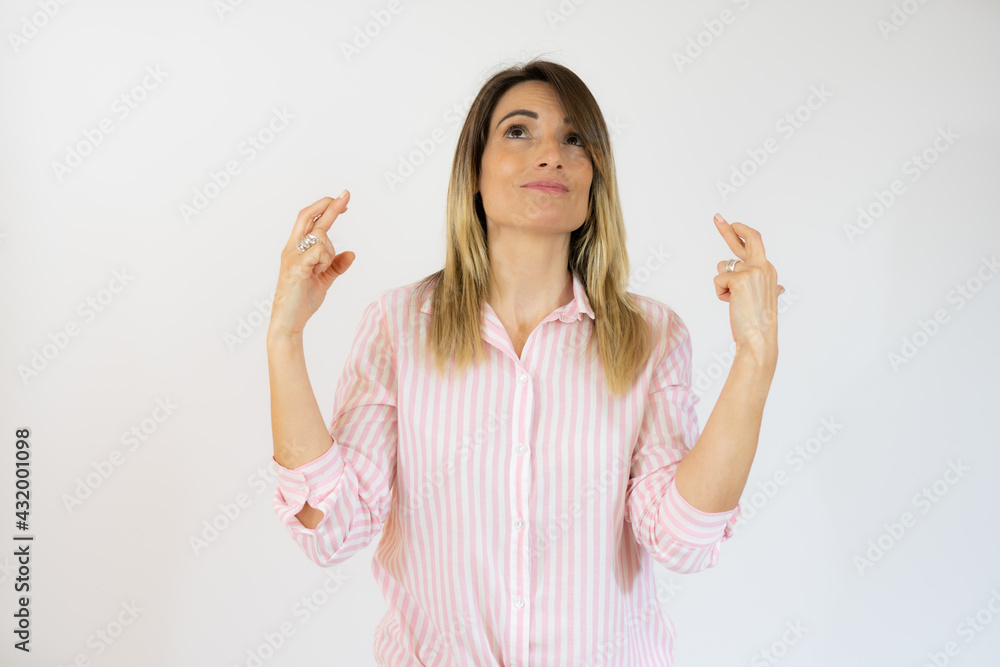 Young woman over isolated white background with fingers crossing Young woman over isolated white background with fingers crossing