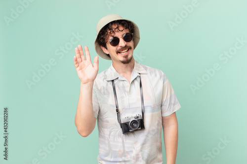 young traveller tourist smiling happily, waving hand, welcoming and greeting you photo