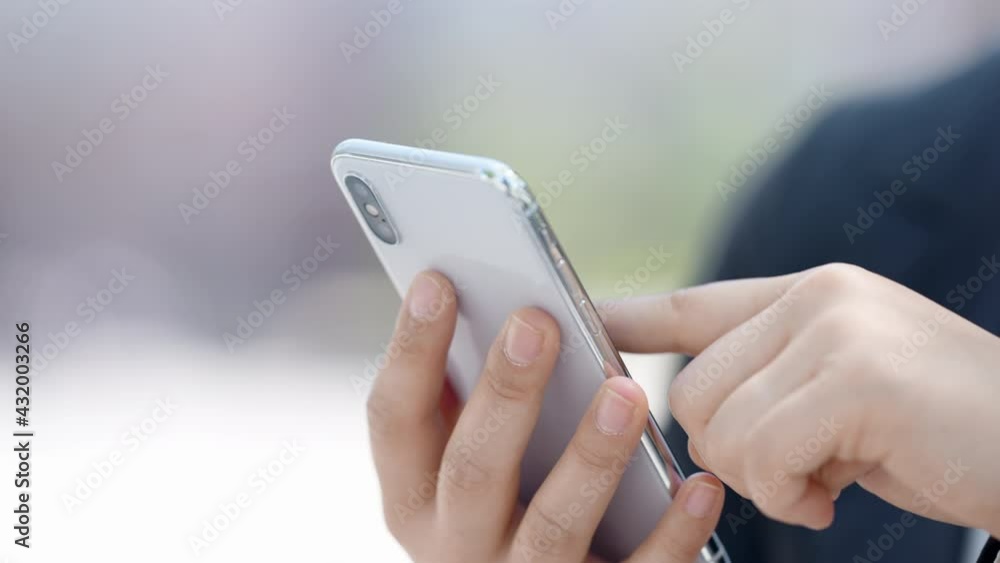 屋外でスマートフォンを操作するマスク姿のビジネスウーマン 屋外でスマートフォンを操作するマスク姿のビジネスウーマン