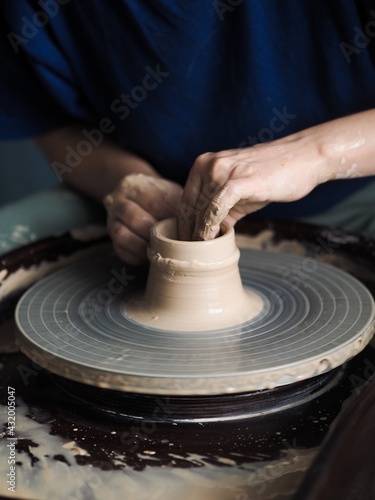 Young female master working on a potter’s wheel, creates clay  dishes, view from above.