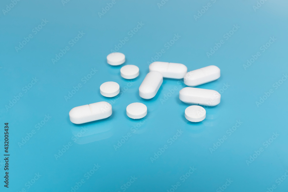 White pills and tablets on a blue medical table. The concept of taking antibiotics, antidepressants or other medications. Medical background. pharmacy concept