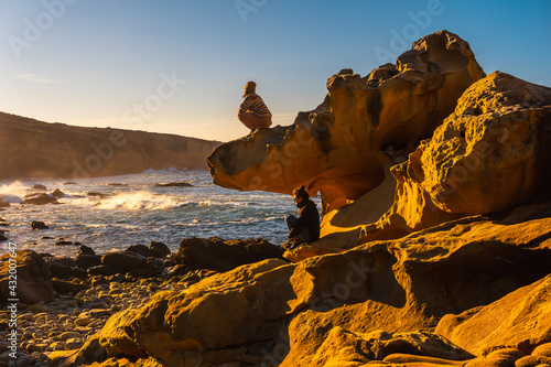A relaxed young woman looking at the sea at sunset in the cove of stones on the Jaizkibel mountain in the town of Pasajes near San Sebastian. Basque Country