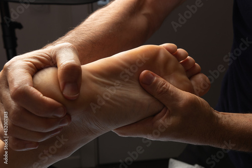 The masseur makes a foot massage. The procedure, hands, osteopath, relaxation, care, medicine, mobility, patient, client