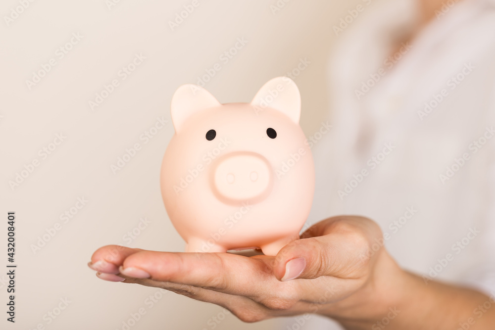 Obraz premium Piggy bank in hand on light background, space for text. Finance, saving money. Business to success and saving for retirement concept