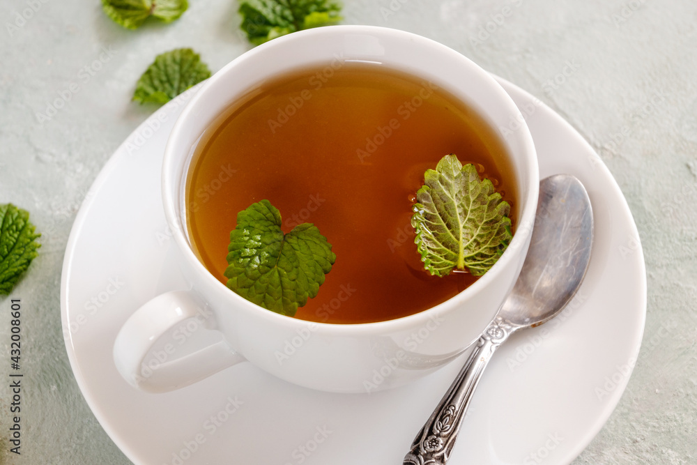 Fresh lemon balm tea in a white cup.