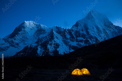 Two illuminated tents at Lobuche East basecamp with the peaks of Taboche and Cholatse in the background in Nepal's Khumbu region. photo