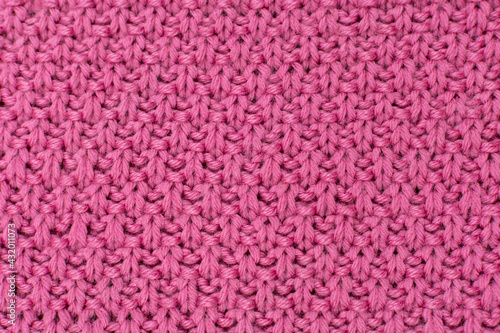 Pink knitted fabric pearl woolen background. The structure of the fabric with a natural texture. Fabric background. Knitted woolen background.