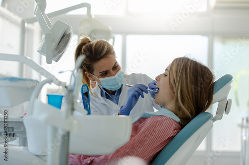 Woman having teeth examined at female dentist.
