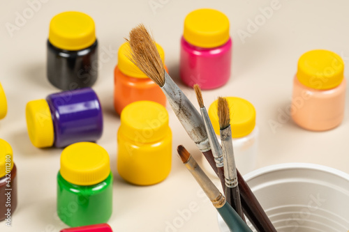 artistic brushes for painting in pot with gouache paints blurred in the background