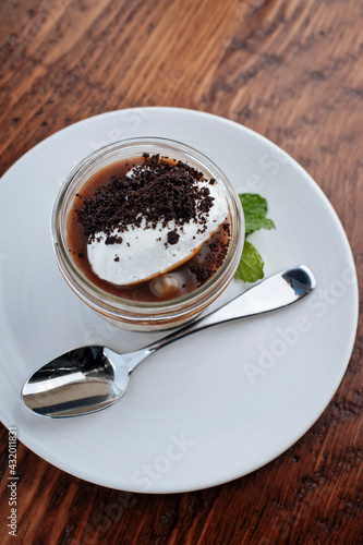 Caramel Panna Cotta with cream, served in a small mason jar garnished with mint. photo