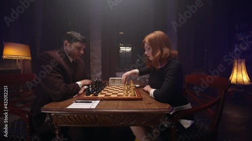 Two chess players man and woman play chess. Debut Accepted Queen's Gambit, King's Gambit, Philidor's Defense. Cinematic filming of a chess game. Antique chess board. This shot can be used for films