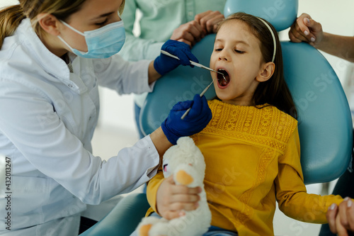 Young girl having check up at dentists surgery with mother.