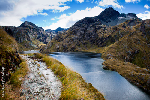 A rocky trail above Lake Harris on day two of the Routeburn Trak (designated as a Great Walk category) in New Zealand's South Island near the town of Glen Orchy. It has superb views of temperate rainforest and alpine environments and is a fabulous multi-day tramp with hut and tent camping options along the way.
