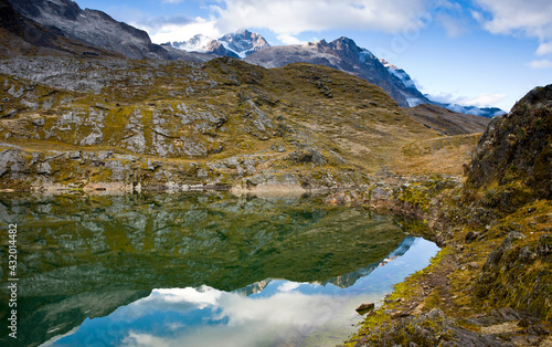 Clouds part above Chilata Lagoon as the reflection reveals granite peaks and glaciers below Mt. Illampu in Bolivia. photo