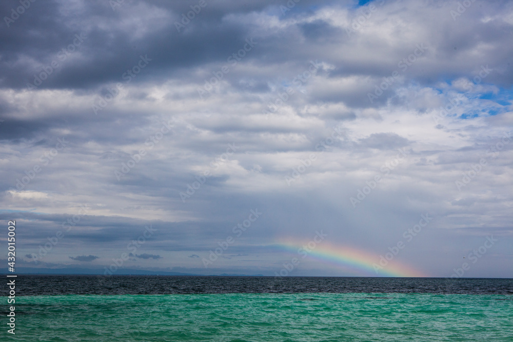 A rainbow appears on the horizon looking out from Coco Plum Island, Belize. A rainbow appears on the horizon looking out from Coco Plum Island, Belize.