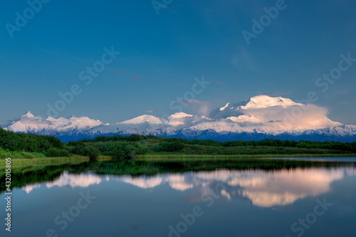 Sunset the first week of summer in Denali National Park, Alaska, casts a soft light on the summits of Mt. McKinley and the Alaska Range, reflecting in Reflection Pond.