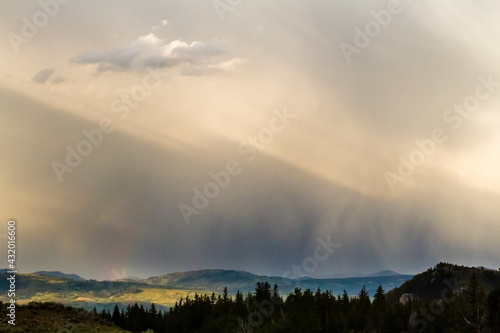 Light shining on rain showers broken up by the Teton Mountains produce a subtle rainbow in Grand Teton National Park, Wyoming. photo